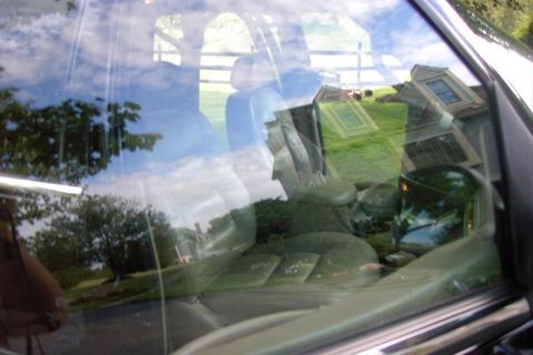 1996 Mercury Grand Marquis - View through a car window shows the interior and a reflection of a house and yard.