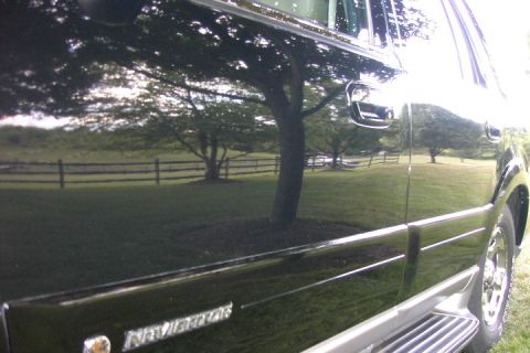 1996 Mercury Grand Marquis - Reflection of trees and a fence on the side of a black SUV.