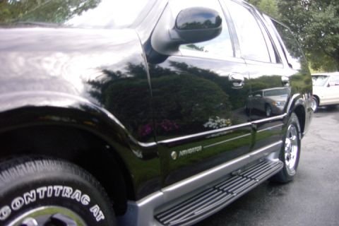 1996 Mercury Grand Marquis - Black Lincoln Navigator SUV shown from the side, with running boards and a reflection of another car.