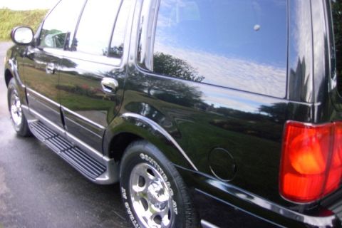 1996 Mercury Grand Marquis - The side of a black SUV is shown, reflecting the sky and trees.