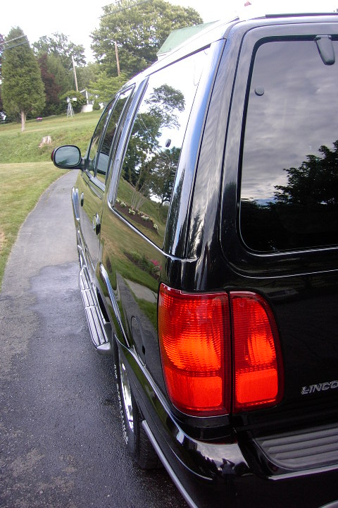 1996 Mercury Grand Marquis - Rear view of a black SUV with tinted windows and chrome running boards.