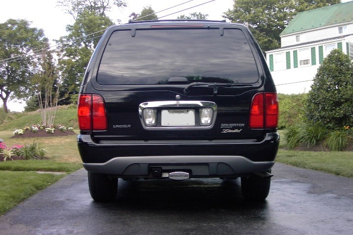Rear view of a black Lincoln Navigator Limited SUV on a wet driveway