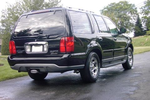 1996 Mercury Grand Marquis - Black Lincoln Navigator Limited SUV parked on a wet road after rain.
