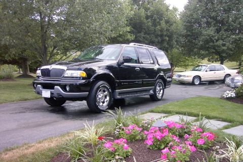 1996 Mercury Grand Marquis - A black SUV is parked on a driveway, with a cream sedan visible in the background.
