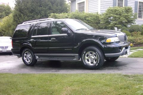 1996 Mercury Grand Marquis - This black SUV, likely from the early 2000s, is parked in a suburban driveway. Another vehicle is partially visible to the left.