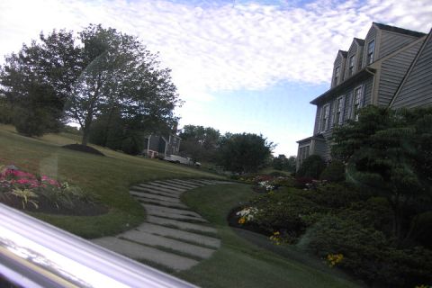 1996 Mercury Grand Marquis - A view of a suburban home's exterior, a stone pathway and lush landscaping under a cloudy sky.