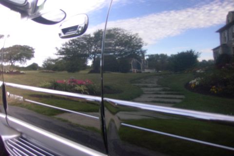 1996 Mercury Grand Marquis - Reflection of a house and garden on the side of a black vehicle.