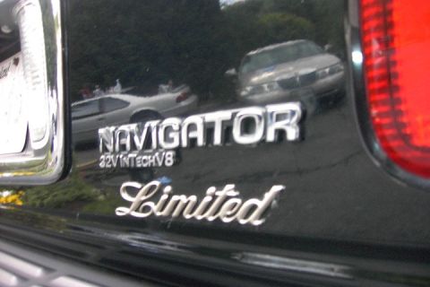1996 Mercury Grand Marquis - Emblems on a black vehicle, with reflections of other cars visible.