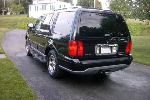 1996 Mercury Grand Marquis - The rear of a black Lincoln Navigator is shown parked on a wet driveway in front of a house.