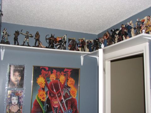 1991 Ford Bronco - A collection of action figures and posters are displayed on shelves against a blue wall, with a doorway to the right.