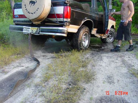 1995 Dodge 1500 - A Ford Bronco is stuck in the dirt, with a person standing nearby.