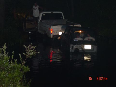 1995 Dodge 1500 - Two trucks are stuck in water at night, with people inside one of them.