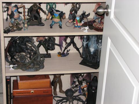 1991 Ford Bronco - A collection of action figures and display pieces are organized on wooden shelves inside a cabinet.