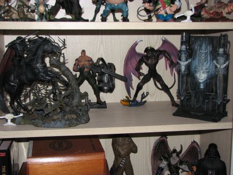 1991 Ford Bronco - A collection of fantasy and sci-fi action figures are arranged on a shelf, with a prominent winged demon figure in the center.
