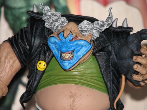 1991 Ford Bronco - A close-up view of a toy figure a clown's head with a blue face and a black leather jacket adorned with a yellow smiley face pin.