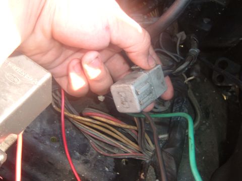 1988 Ford Bronco - Close-up of a hand holding a car's electrical relay connector with visible wiring.