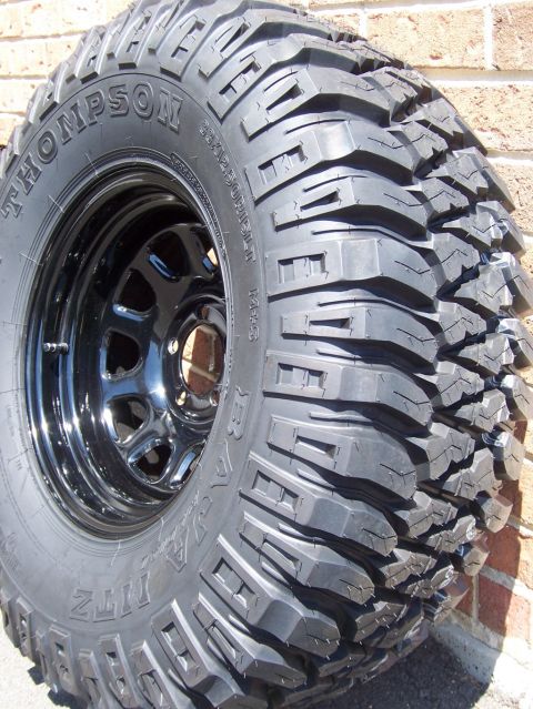 1996 Jeep Grand Cherokee - A close-up view of a black off-road tire and rim assembly, showing its tread pattern.