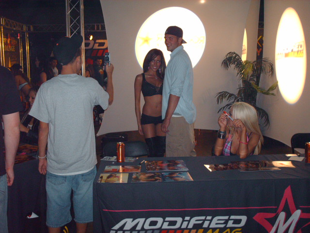 People posing at a promotional event with "MODIFIED SUPERMOTORS" banner