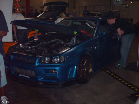 1995 Ford Probe - A blue Nissan Skyline GT-R R34 is displayed with its hood open, revealing the engine bay.