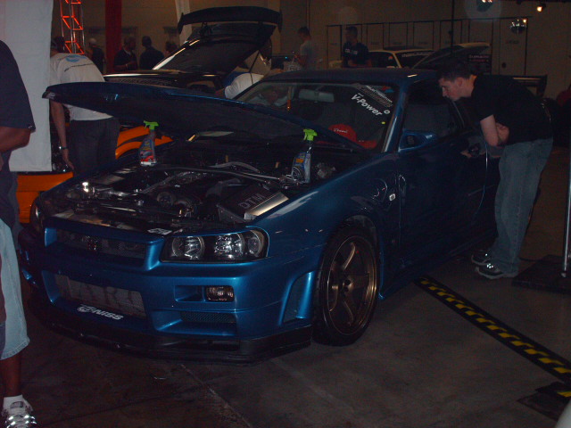 Blue Nissan Skyline GT-R R34 with hood open, someone looking inside