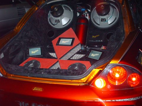 1995 Ford Probe - The custom audio system in the trunk of a red car is visible, subwoofers and screens.