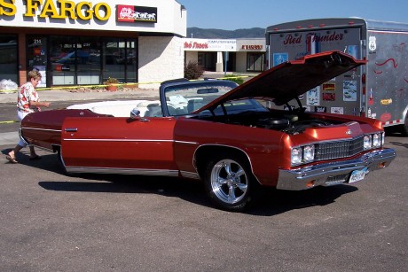 1972 Ford Ranchero - A red convertible with its hood open is parked in front of a building, with a person standing by the driver's door.