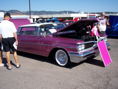 1972 Ford Ranchero - A pink 1959 Pontiac Bonneville is displayed with its hood open at an outdoor event.