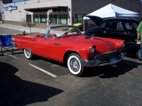 1972 Ford Ranchero - A bright red convertible with classic styling is parked next to a black car at an outdoor event.