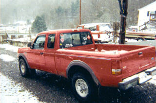 1997 Ford Ranger - A red 1997 Ford Ranger pickup truck is parked on a snowy road with another vehicle and a boat trailer visible in the background.