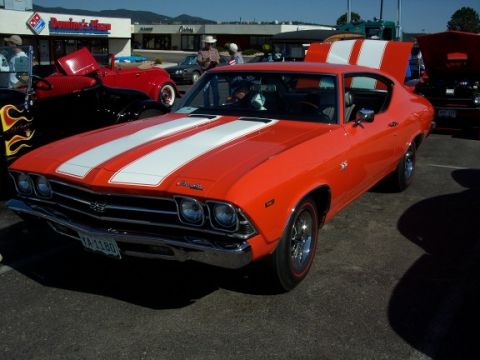 1972 Ford Ranchero - Orange 1969 Chevrolet Chevelle SS with white racing stripes, parked at an outdoor event.
