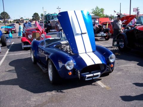 1972 Ford Ranchero - A blue convertible with white racing stripes and its hood open is parked at an outdoor car show.