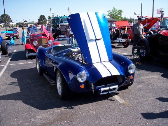 Blue and white striped convertible with hood open, parked at an outdoor event