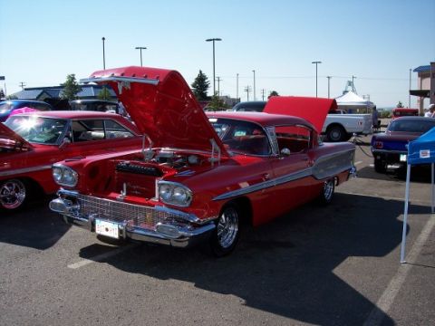 1972 Ford Ranchero - A red 1958 Pontiac Bonneville coupe is displayed with its hood open at an outdoor event.