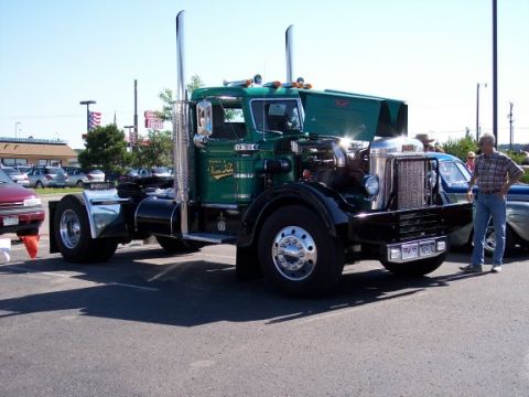 1972 Ford Ranchero - A classic green semi-truck is displayed with its hood open, parked alongside other vehicles at an outdoor event.