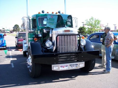 1972 Ford Ranchero - A large green semi-truck is parked at an outdoor event, with its hood open, revealing the engine area.