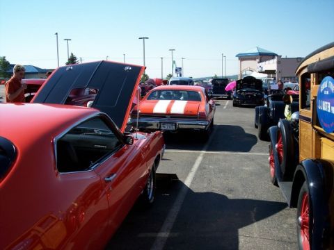 1972 Ford Ranchero - A collection of vintage automobiles are displayed outdoors on a sunny day, with several owners attending to their vehicles.