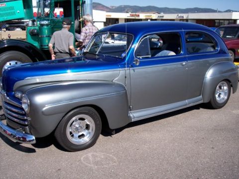 1972 Ford Ranchero - A two-tone blue and silver sedan from the mid-1940s is parked at an outdoor event.