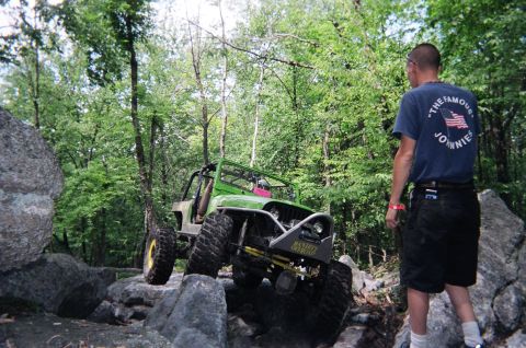 1976 GMC C/K Pickup - A person watches a modified green off-road vehicle traverse a rocky trail.