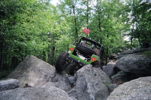 1976 GMC C/K Pickup - Off-road vehicle navigating a rocky trail in a forest.
