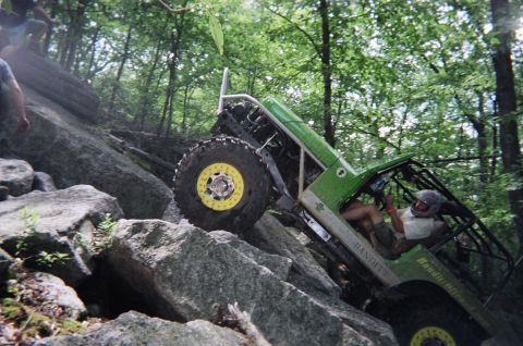 1976 GMC C/K Pickup - A custom-built buggy navigates a challenging rocky terrain in a wooded area.