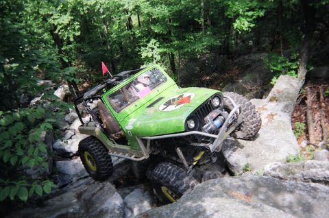1976 GMC C/K Pickup - This modified Jeep is navigating a challenging rocky terrain on an off-road trail.