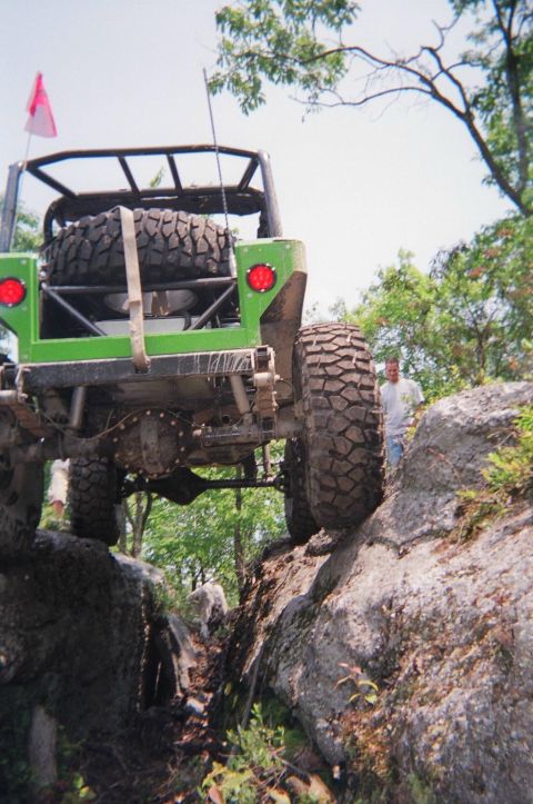1976 GMC C/K Pickup - This modified off-road vehicle navigates a rocky trail, its heavy-duty suspension and large tires.