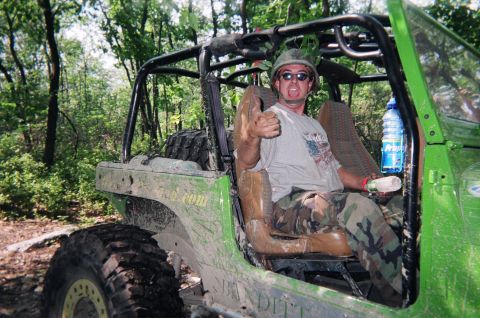1976 GMC C/K Pickup - Off-road enthusiast in a modified vehicle gives a thumbs-up gesture while wearing camouflage attire.