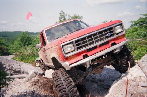 1976 GMC C/K Pickup - This modified pickup truck is shown off-roading on a challenging rocky course.