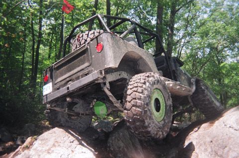 1976 GMC C/K Pickup - This heavily modified off-road vehicle navigates a rocky trail with its rear end visible.