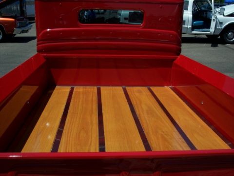 1972 Ford Ranchero - A bright red pickup truck bed features a polished wooden floor with dark separators, seen from the rear.