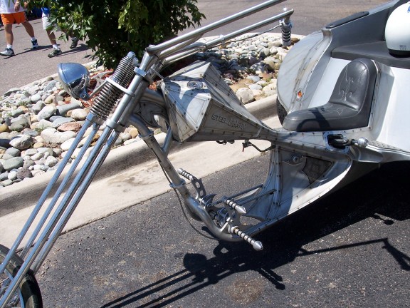 Custom motorcycle with steel body and sidecar, showing front forks and seat