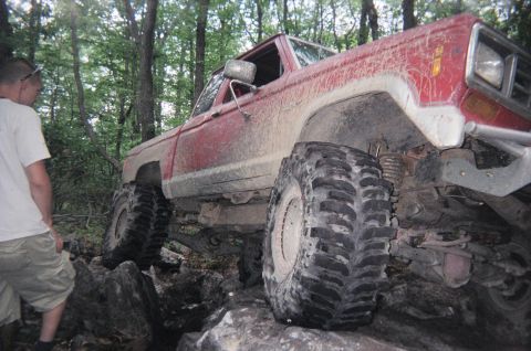 1976 GMC C/K Pickup - Modified off-road truck with oversized tires tackling a challenging rocky trail.