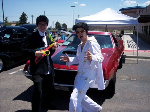 1972 Ford Ranchero - Two people in costumes pose next to a red car at an outdoor event.