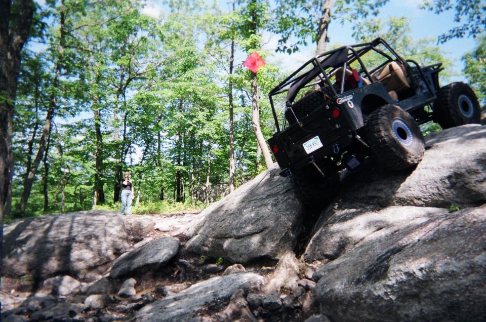 Black off-road jeep climbing large rocks on a trail